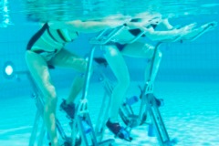 Zwei Personen Unterwasser, die eine Übung auf Aqua Bikes ausführen