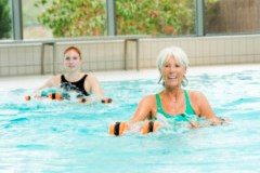 Zwei Personen im Wasserbecken, mit Aquahanteln in der Hand