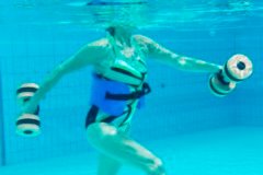 Eine Person Unterwasser, die mit Aquahanteln trainiert