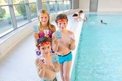 Drei Kinder, die ihre Schwimmabzeichen zeigen