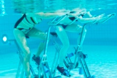 Zwei Personen Unterwasser, die auf Aqua Bikes trainieren